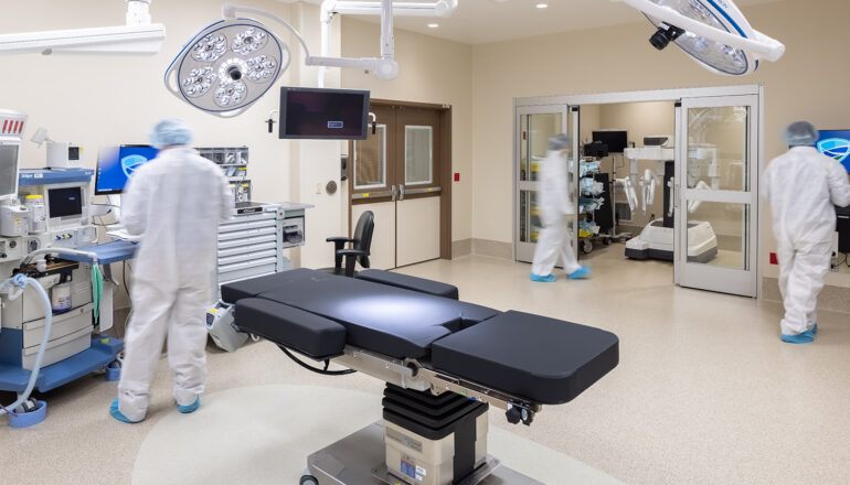 Surgeons work inside the robotic OR in the MMC Ashland Surgery Center. A surgery robot is stored inside a small "garage" on the side of the room